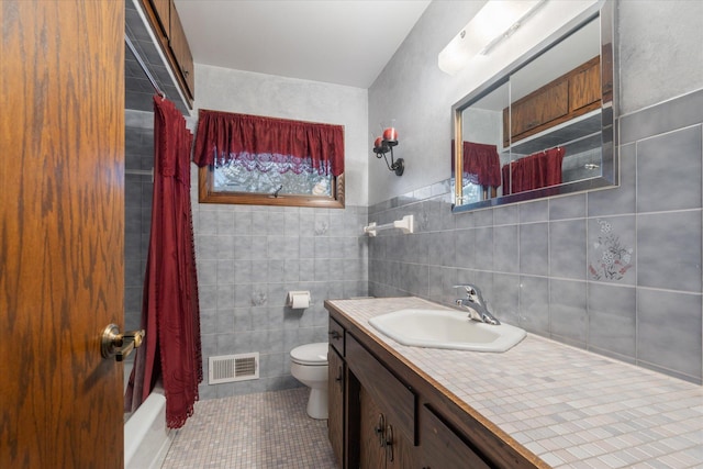 full bathroom with toilet, shower / tub combo, tile patterned floors, and tile walls