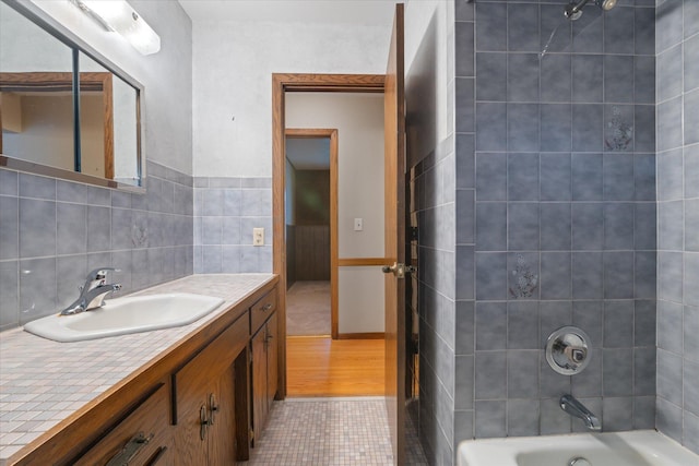 bathroom with tile patterned flooring, vanity, washtub / shower combination, and tile walls