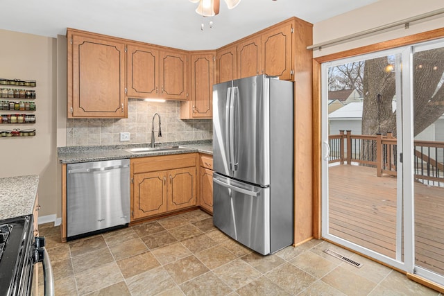 kitchen featuring appliances with stainless steel finishes, sink, backsplash, and ceiling fan