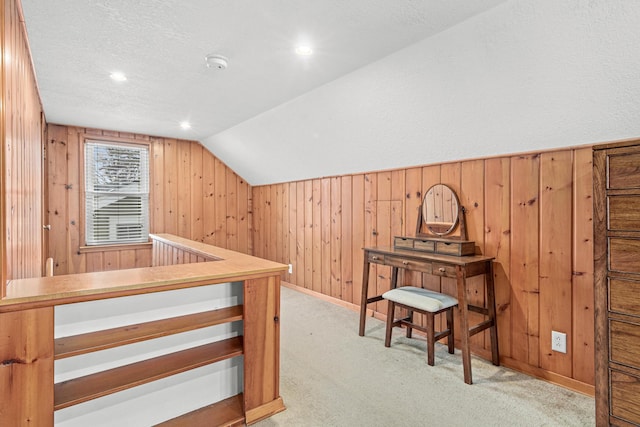 additional living space featuring lofted ceiling, light carpet, and wood walls