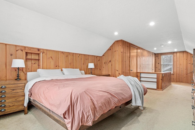 carpeted bedroom featuring lofted ceiling, a textured ceiling, and wood walls