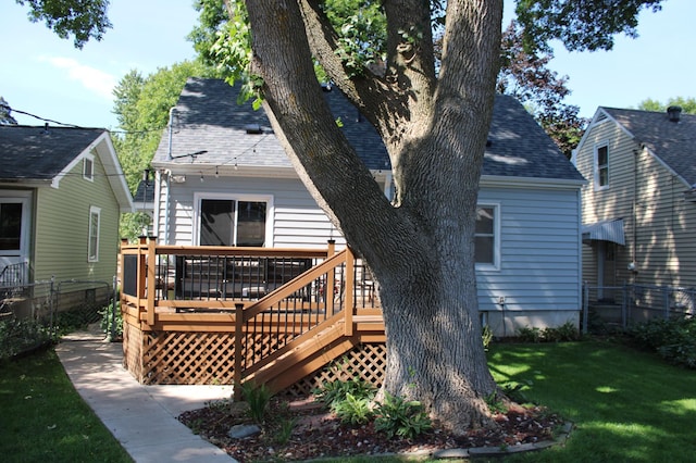 back of property featuring a wooden deck and a yard