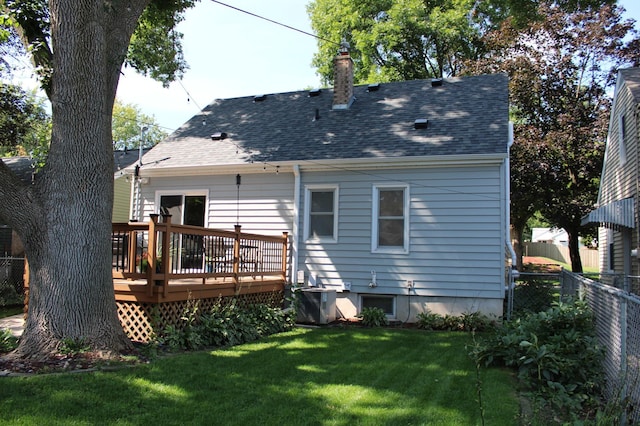 rear view of property with cooling unit, a wooden deck, and a lawn