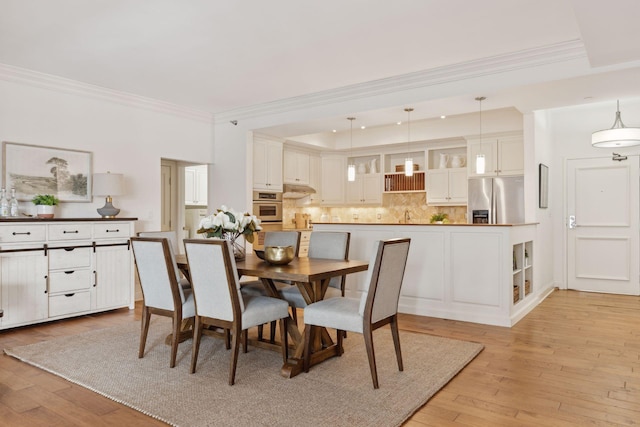 dining room featuring light wood-type flooring and crown molding