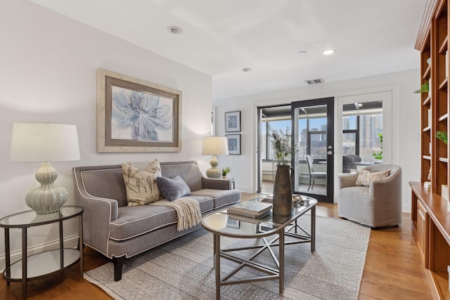 living area with light wood finished floors, recessed lighting, visible vents, and baseboards