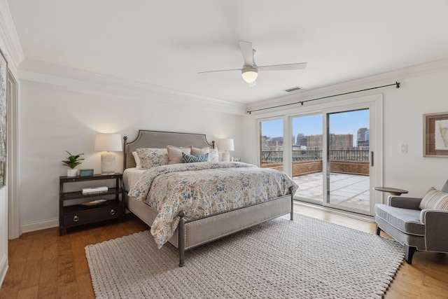 bedroom featuring dark wood finished floors, a view of city, access to outside, and crown molding