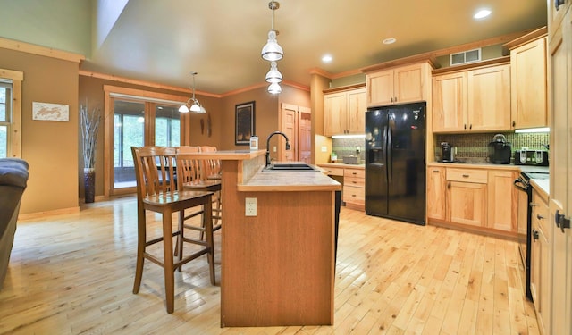 kitchen with light brown cabinets, sink, hanging light fixtures, and black appliances