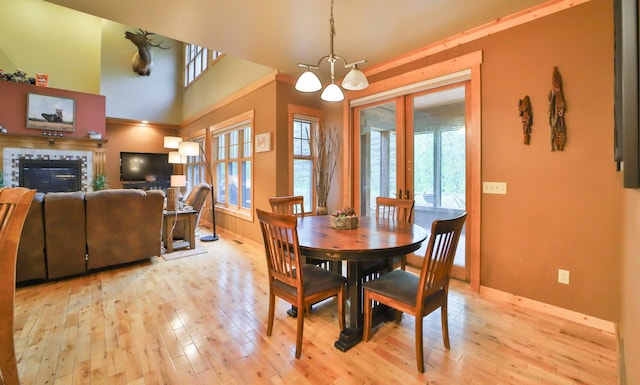 dining room featuring ornamental molding, light hardwood / wood-style flooring, a tile fireplace, and an inviting chandelier