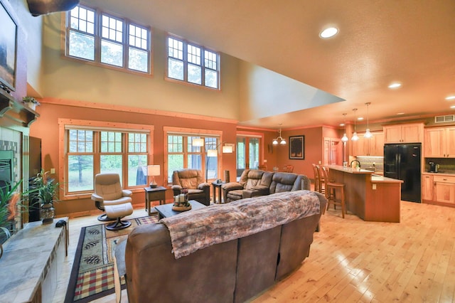 living room featuring a chandelier, a high ceiling, and light hardwood / wood-style flooring