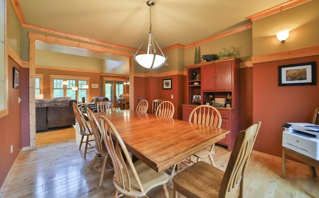 dining room with light wood-type flooring and crown molding