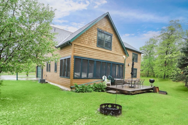 rear view of house with central air condition unit, a lawn, and a sunroom