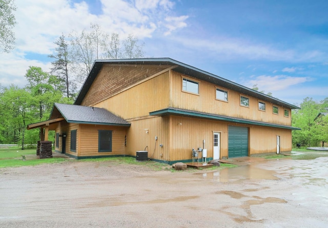 view of side of home featuring a garage and cooling unit