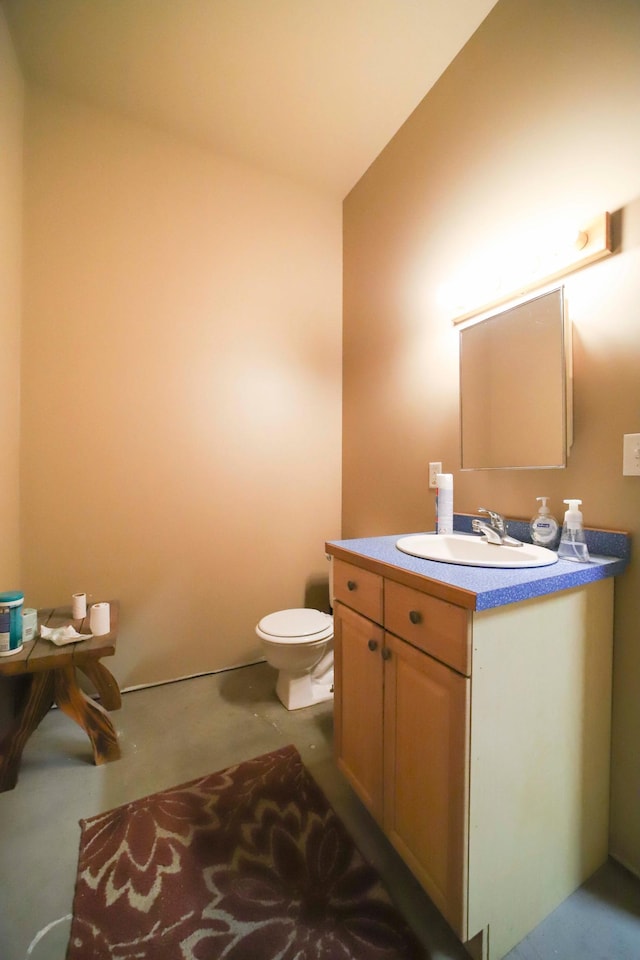 bathroom with vanity, toilet, and concrete floors