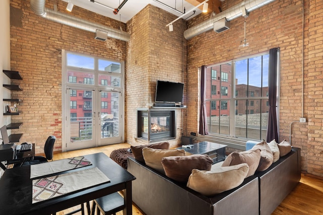 living room with a wealth of natural light, a towering ceiling, and brick wall