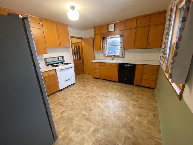 kitchen with dishwasher, white range with gas stovetop, stainless steel refrigerator, and sink