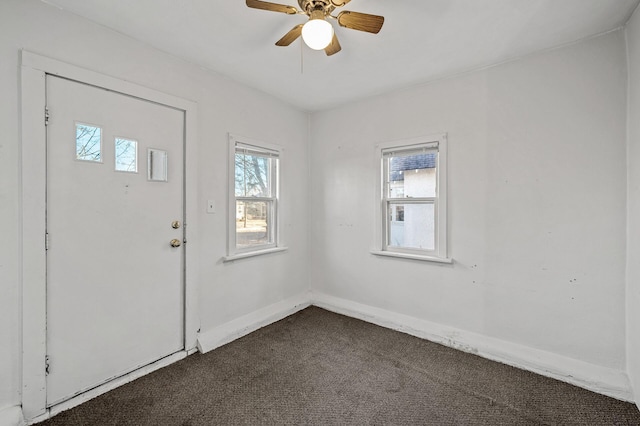 entryway featuring ceiling fan and dark colored carpet