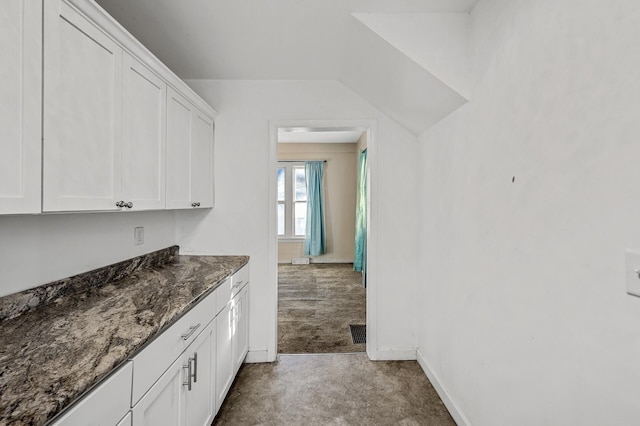 bar with white cabinets, carpet flooring, and dark stone countertops