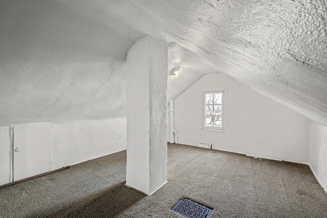 additional living space with dark colored carpet, lofted ceiling, and a textured ceiling