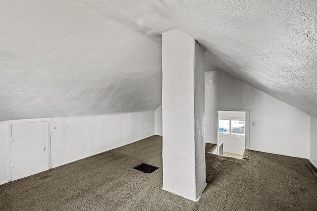 bonus room with vaulted ceiling, dark carpet, and a textured ceiling