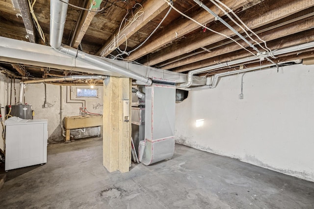 basement featuring sink, separate washer and dryer, heating unit, and water heater