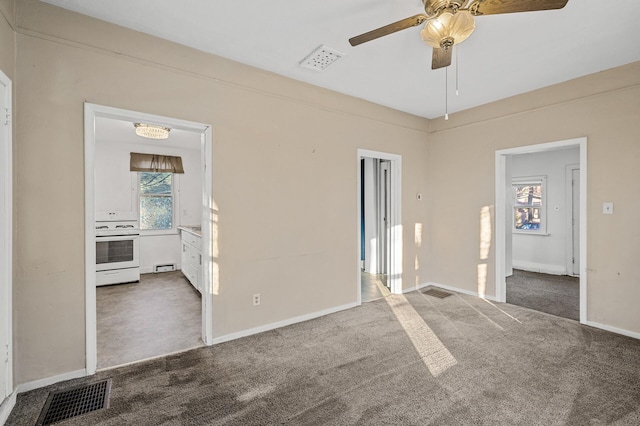 carpeted empty room featuring ceiling fan and a baseboard heating unit