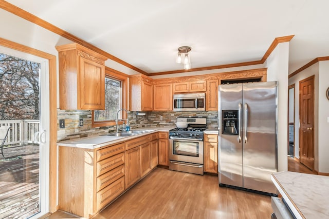 kitchen featuring sink, stainless steel appliances, backsplash, light wood-type flooring, and ornamental molding