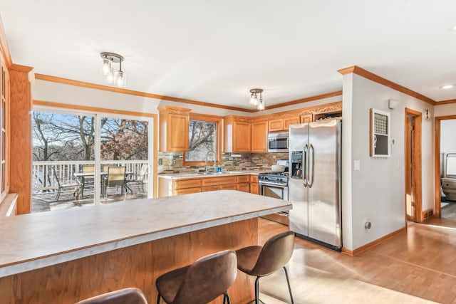 kitchen featuring light wood-type flooring, backsplash, ornamental molding, stainless steel appliances, and sink