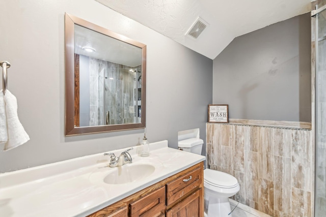 bathroom with vaulted ceiling, a textured ceiling, an enclosed shower, toilet, and vanity