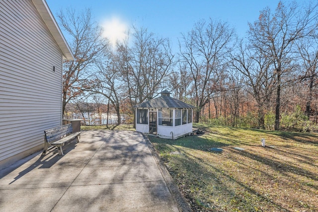 view of home's exterior featuring a sunroom, a patio, and a lawn