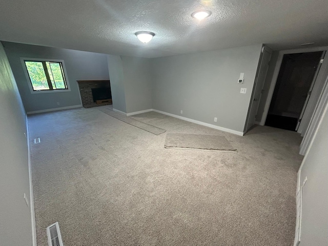 unfurnished living room featuring a fireplace, carpet, and a textured ceiling