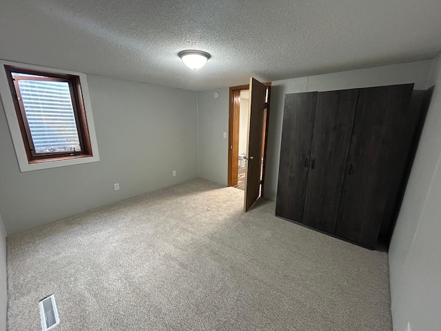 unfurnished bedroom with a textured ceiling and light carpet