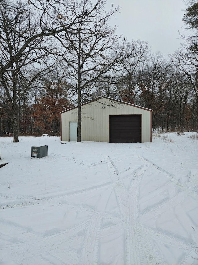 snow covered structure featuring a garage