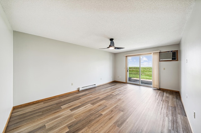 spare room featuring a textured ceiling, ceiling fan, a baseboard heating unit, an AC wall unit, and hardwood / wood-style floors