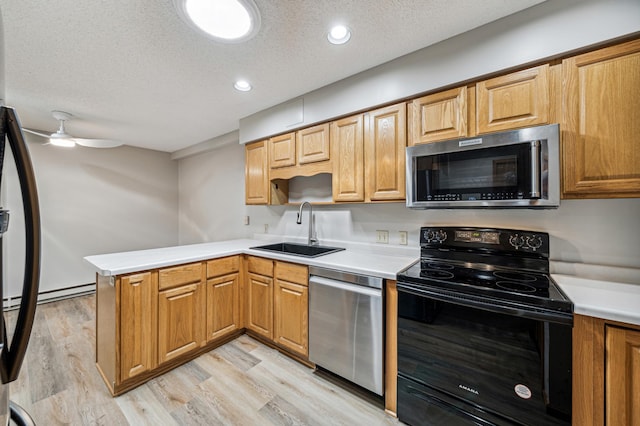 kitchen with kitchen peninsula, light wood-type flooring, a textured ceiling, stainless steel appliances, and sink