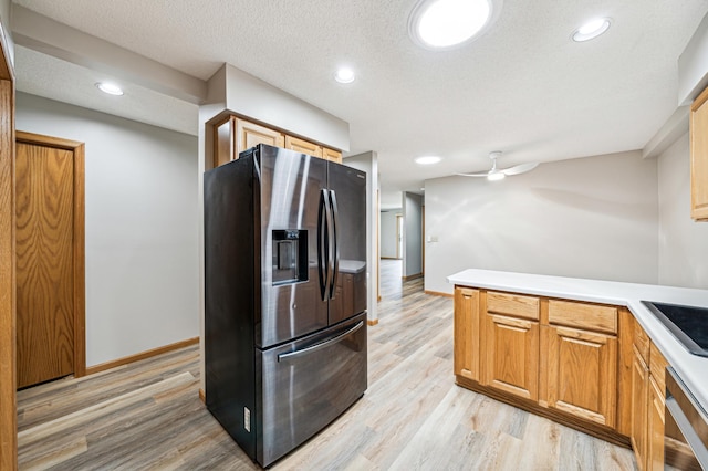 kitchen featuring ceiling fan, stainless steel appliances, a textured ceiling, and light wood-type flooring