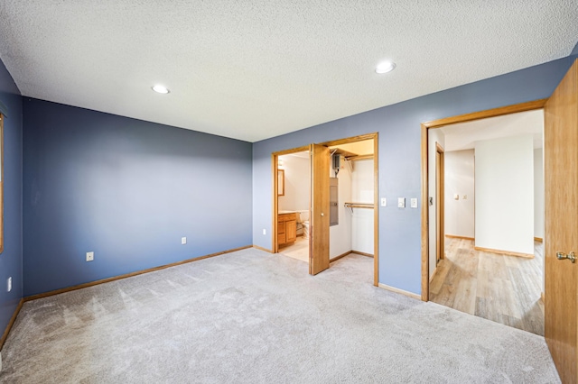 unfurnished bedroom featuring light carpet, a textured ceiling, connected bathroom, and a closet