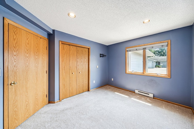 unfurnished bedroom featuring a textured ceiling, a closet, light colored carpet, and baseboard heating