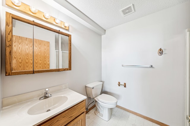 bathroom with vanity, toilet, and a textured ceiling