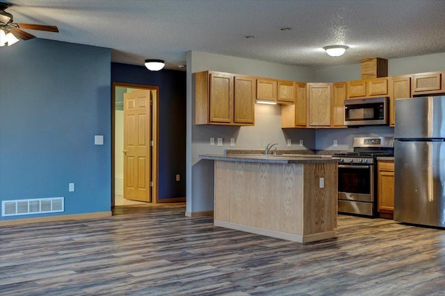 kitchen with ceiling fan, appliances with stainless steel finishes, a textured ceiling, dark hardwood / wood-style flooring, and light brown cabinets