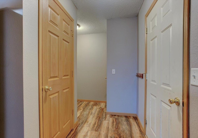 hall with light hardwood / wood-style flooring and a textured ceiling