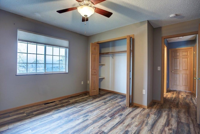 unfurnished bedroom with dark hardwood / wood-style flooring, ceiling fan, a closet, and a textured ceiling