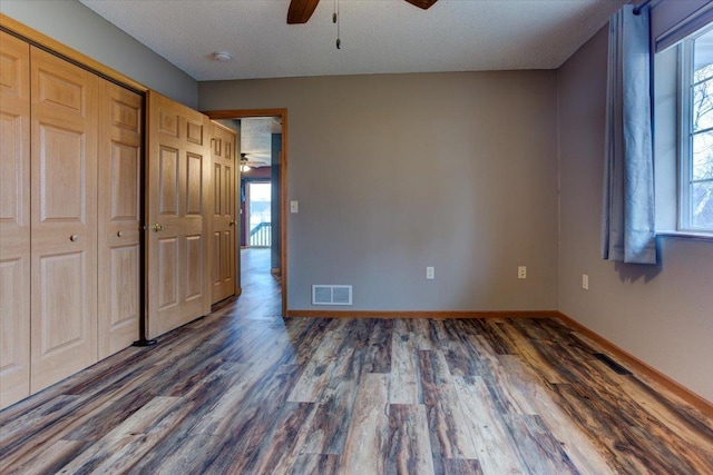 unfurnished bedroom featuring dark wood-type flooring, a closet, and ceiling fan