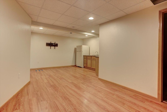 spare room featuring a drop ceiling, sink, and light hardwood / wood-style flooring