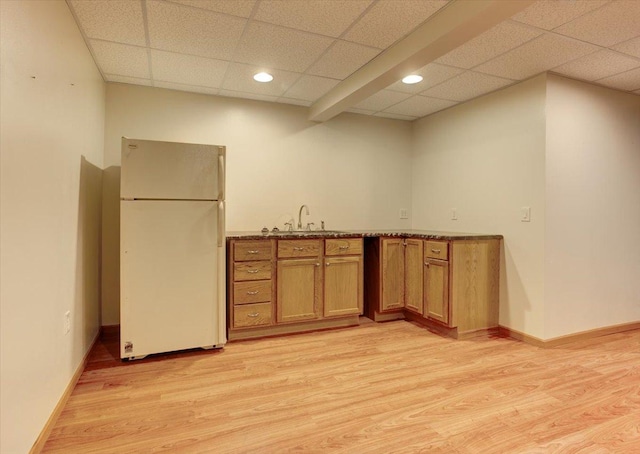 kitchen with a drop ceiling, sink, light hardwood / wood-style flooring, and white fridge