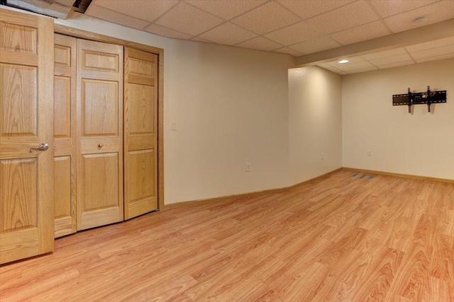 basement featuring a paneled ceiling and light hardwood / wood-style flooring