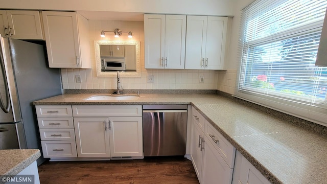 kitchen featuring appliances with stainless steel finishes, white cabinetry, a sink, and decorative backsplash