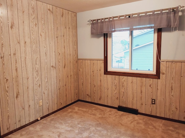 empty room featuring light carpet and wooden walls