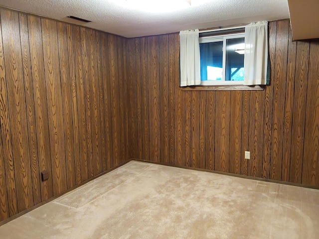 interior space featuring a textured ceiling, wood walls, and light carpet