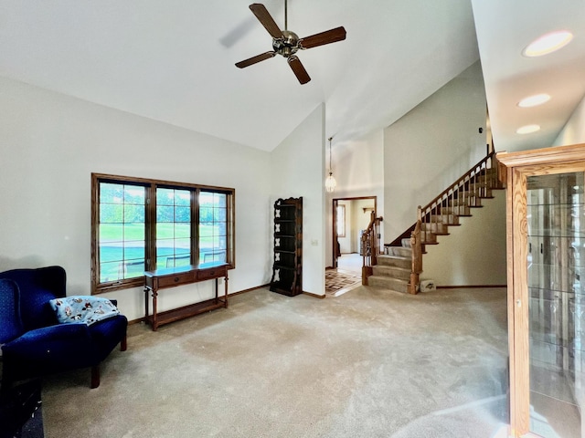 living area with ceiling fan, light colored carpet, and high vaulted ceiling