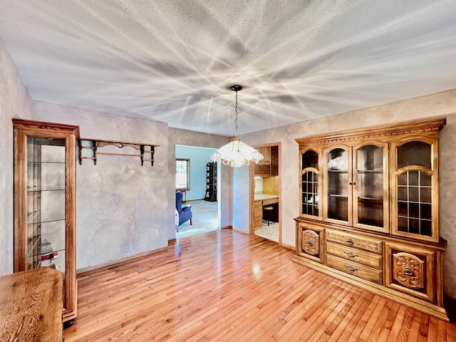 unfurnished dining area with hardwood / wood-style floors and an inviting chandelier